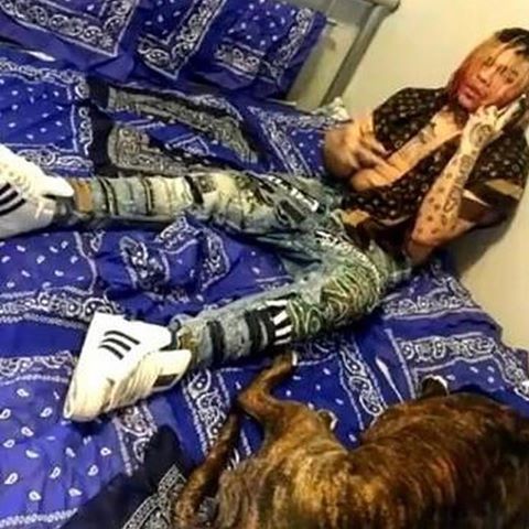 6ix9ine Lays on a Bed Spread made of Blue Bandanas